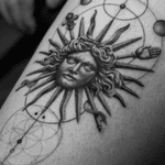 Experience fine line and micro realism by Light Grays in this stunning black and gray tattoo featuring a geometric Greek sun motif.