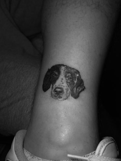 A stunning black-and-gray tattoo of a realistic dog portrait, expertly done by tattoo artist Ruby Rowland.