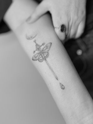 Stunning black and gray tattoo by Vera featuring a delicate butterfly and a detailed dagger, done in micro realism style.