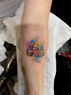 Beautiful tattoo by Ryan Mckenzie featuring a sketch of a keyboard with game inspired elements in fine line and watercolor style.