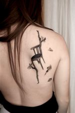 A poetic surrealist realism tattoo in black and grey, showing an antique chair perched on a gnarled branch growing from the skin. This dreamlike composition symbolises solitude and suspended memory.