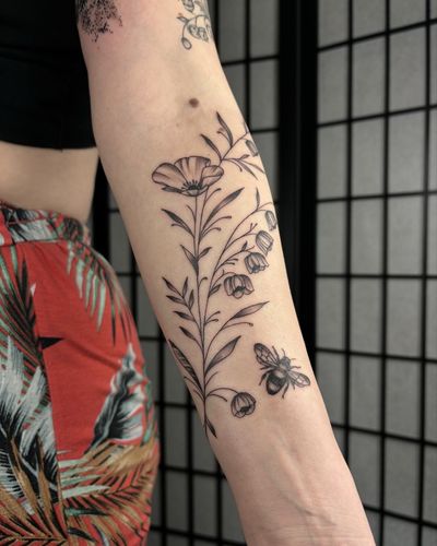 A black and gray fine line tattoo featuring a bee and a flower, created with intricate dotwork by Alice Hope Tattoo.