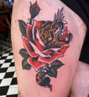 Stunning traditional tattoo by Megan Foster featuring a fierce leopard, panther, and beautiful rose motif.