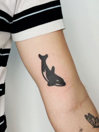 Hand-poked blackwork tattoo of majestic killer whale by artist Laura. Bold lines and solid colors create a striking visual impact.