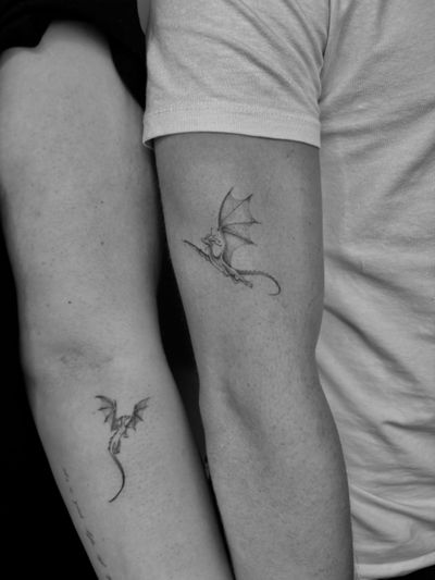 Two intricately detailed black and gray dragon tattoos by Ruth Hall, designed to complement each other.