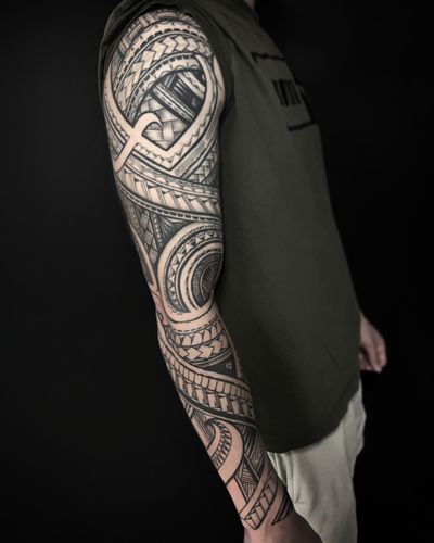 Intricate blackwork tattoo by Justin JP Param, featuring geometric patterns inspired by Polynesian and Maori motifs.