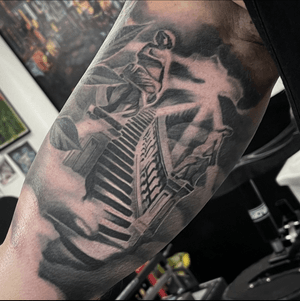 A realistic black and gray tattoo featuring a statue on stairs leading to heaven, by Cara Hayward.