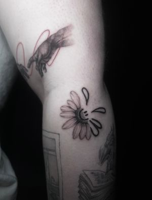 Unique black and gray illustrative tattoo by Lauren featuring a flower and smiley face design.