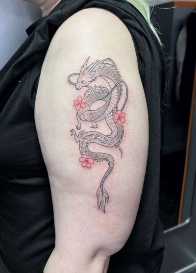 An illustrative black and gray tattoo featuring a dragon intertwined with a delicate flower, done by artist Inna with fine line details.