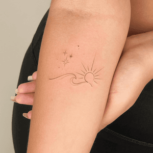 Fine line ornamental tattoo featuring a sun, star, sparkle, and waves by Larissa.