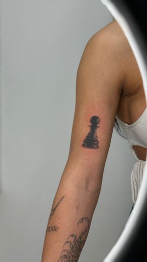 Bold blackwork tattoo by Rollo featuring halftone print pawn in a chess motif.