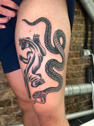 This tattoo by Barney Coles features a traditional style motif of a snake and panther in black and gray ink.