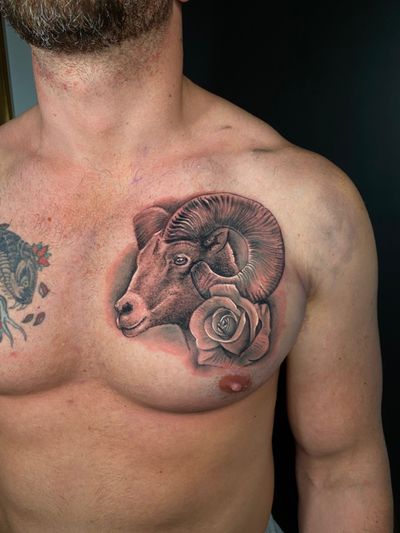 Stunning black and gray tattoo featuring a majestic goat and delicate rose, expertly crafted by Marie Terry.