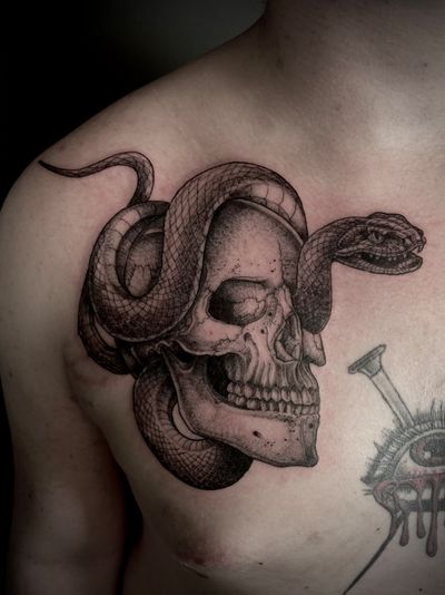 Get a unique black and gray illustrative tattoo of a snake and skull by Kat Jennings. Fine line details for a stunning result.