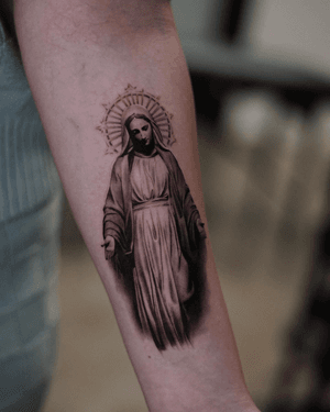 This black and gray tattoo by Kenny Go features a detailed micro realism depiction of the holy mary in a religious motif.