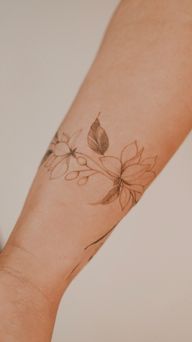 A delicately shaded fine-line floral bracelet wrapped around the forearm, featuring magnolia and nutmeg flowers, drawn freehand to complement the body's lines.