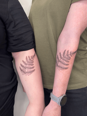 A set of matching black and gray fine line fern tattoos by artist Joanna Webb, showcasing elegant botanical designs.