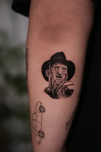 A striking black and gray micro-realism tattoo of iconic horror character Freddy Krueger, expertly crafted by Kenny Go.