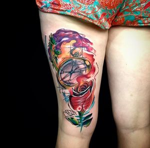 Get a vibrant new school watercolor tattoo of a flower and compass by artist Sandro Secchin on your upper leg. Stand out with this unique design.