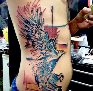Beautiful watercolor eagle tattoo on the ribs by Sandro Secchin. Bold and vibrant colors bring this majestic bird to life.