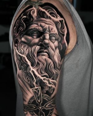 A black and gray realism tattoo featuring a cross with symbols of Odin, Zeus, lightning, and Celtic knotwork. By artist Ember.