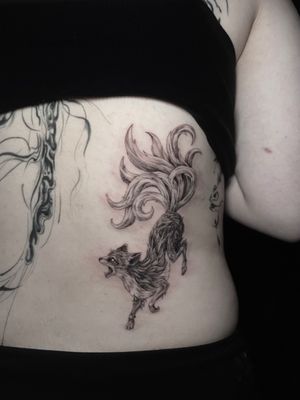 Illustrative black and gray tattoo of a fox with 9 tails, inspired by Japanese mythology, by artist Lauren.