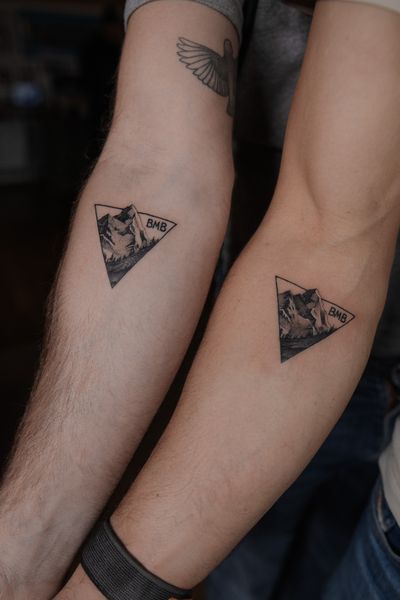 Matching black and grey, finelined mountain tattoos