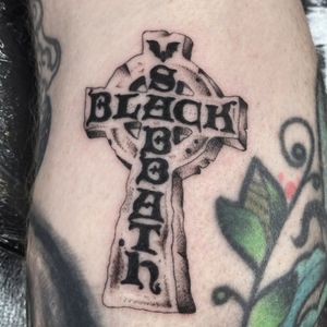 Get a bold and powerful tattoo combining a cross and Black Sabbath motifs, designed by the talented Megan Foster.
