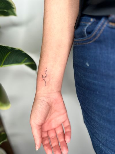 Get inspired by this delicate fine line tattoo of a wave crafted by the talented artist jadeshaw_tattoos. A beautiful and simplistic design for ocean lovers.