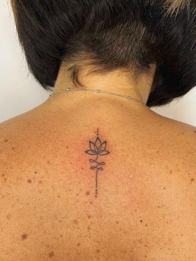 An ornamental unalome design created with fine line handpoke technique by Laura.