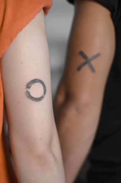 Experience Maria's unique style with this minimalist enso circle tattoo incorporating brush strokes and X motif.