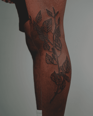 A blackwork tattoo featuring intricate floral etchings on dark skin, created by artist Alona Hamova.