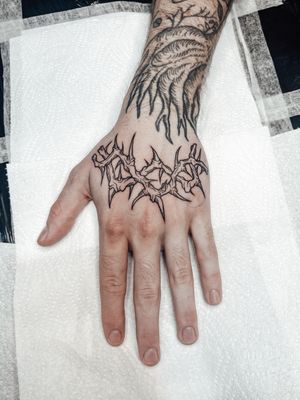 Illustrative tattoo by Alexandra Mulhall featuring a woodcut style with intricate thorns design.