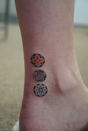 This illustrative tattoo combines traditional Korean dancheong patterns with delicate flowers for a unique and beautiful design by HWIZI.