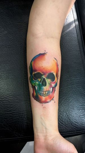 Vivid new school watercolor skull tattoo by artist Sandro Secchin, perfect for forearm placement.