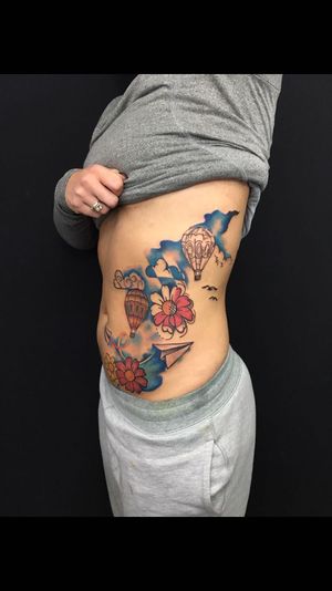Vibrant new school tattoo by Sandro Secchin, showcasing a delicate flower and whimsical balloon design on the ribs.