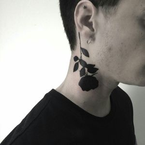 Interesting solid black rose with thorny, leafy stem on the side of the neck tattoo, interesting direction