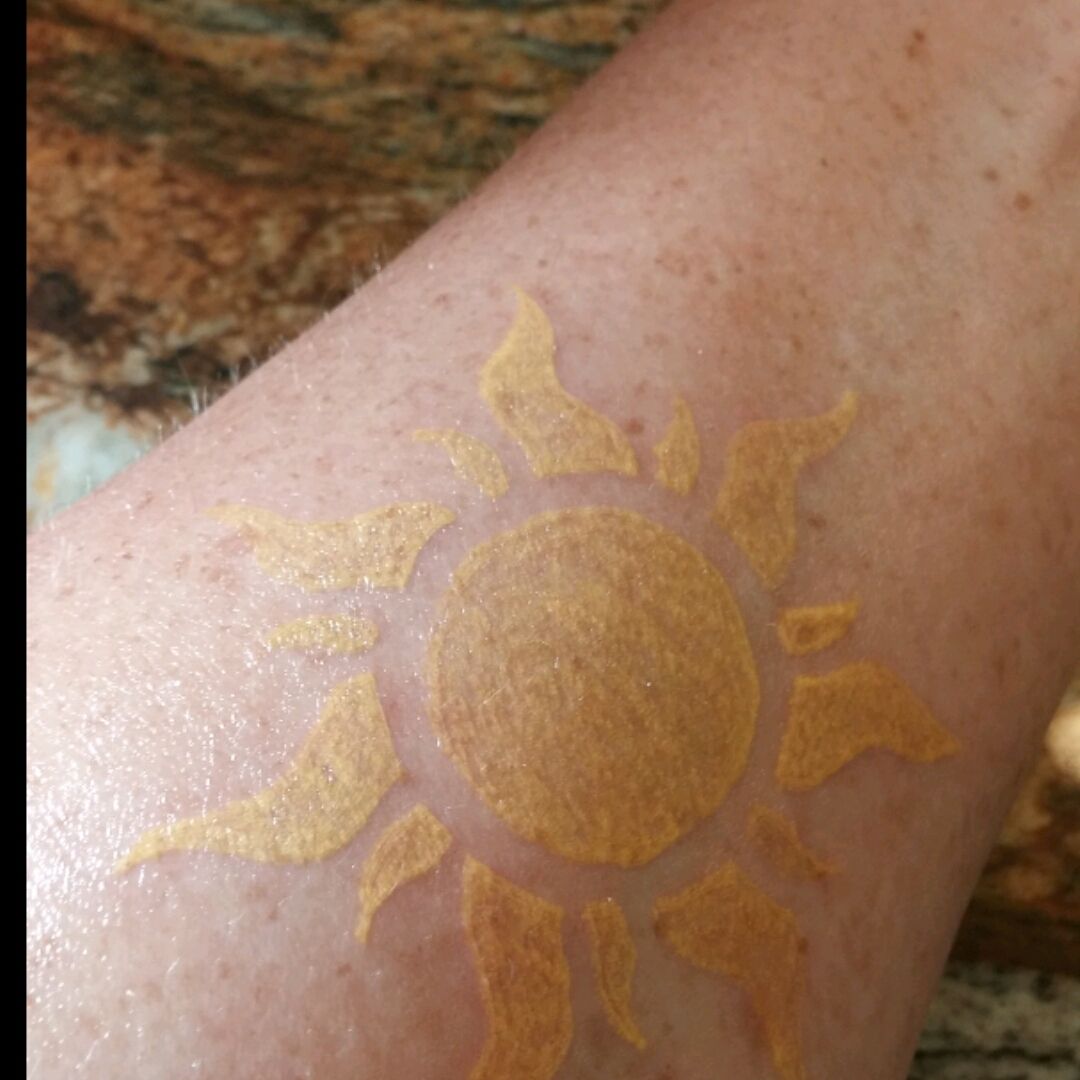 Fine line sun tattoo placed on the tricep