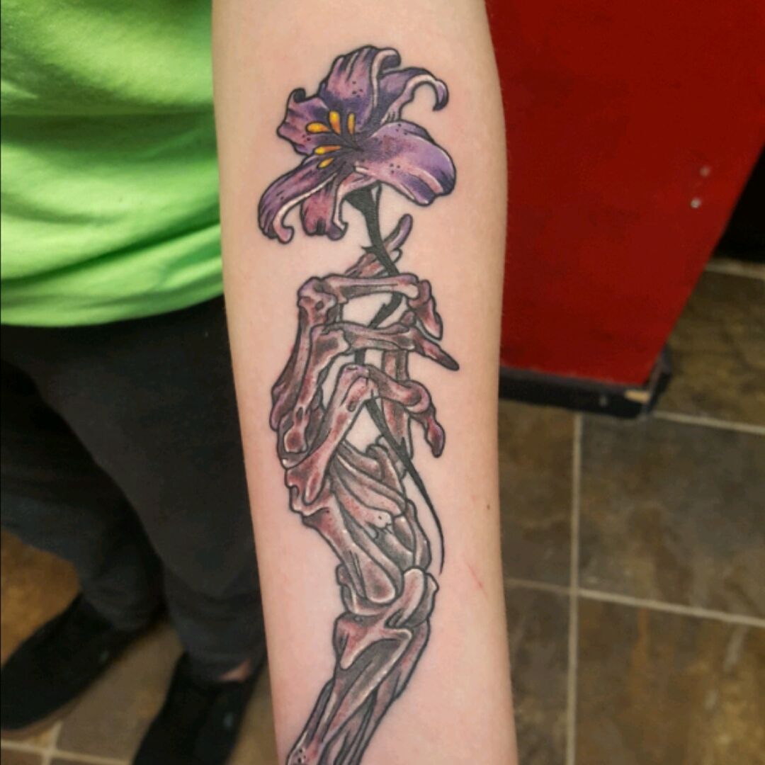 Fine line hand holding flower tattoo on the rib