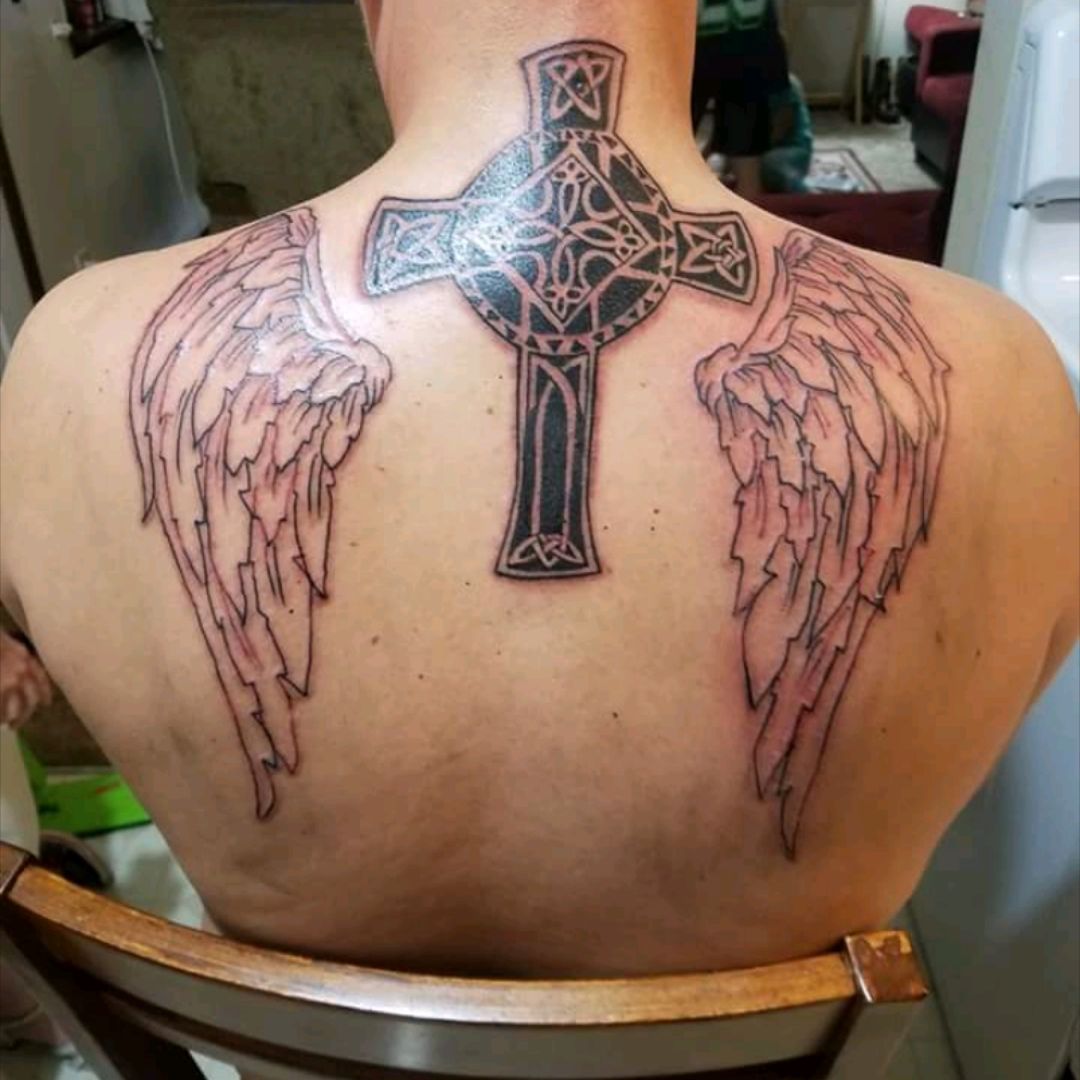 This is by far the largest 1st tattoo on a client we've done! Full back  piece cross with wings and custom letterings. Parts healed and