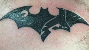 The Bat symbol with a silhouette of the Batman.