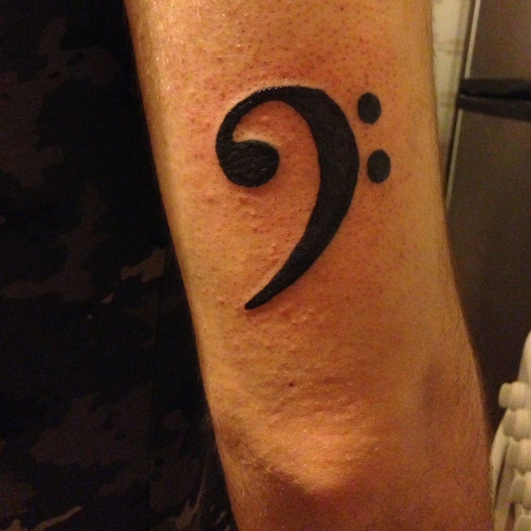 Little wrist tattoo of a bass clef and a treble clef