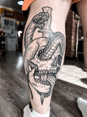 Fine line illustrative tattoo by Alexandra Mulhall featuring a snake, skull, dagger, engraving, and woodcut elements.