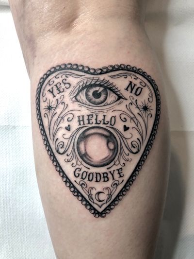 Stunning black and gray tattoo with small lettering by Amandine Canata featuring a mystical heart, eye, patch, and Ouija board design.