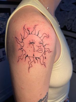 Beth Farbrother's unique design features a sun, baby, kid, and tear, beautifully illustrated in a striking tattoo.