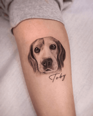 Detailed black-and-gray portrait of a pet dog, done in fine lines and small lettering by tattoo artist Constanza.