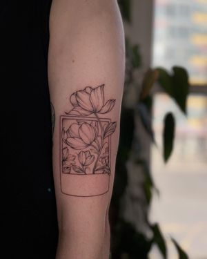 Exquisite floral fine line tattoo of a picture polaroid frame with delicate flowers, expertly done by artist Anggi Kokovikas.