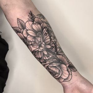 Stunning black and gray tattoo by Lawrence Canham featuring a delicate moth and intricate floral design.