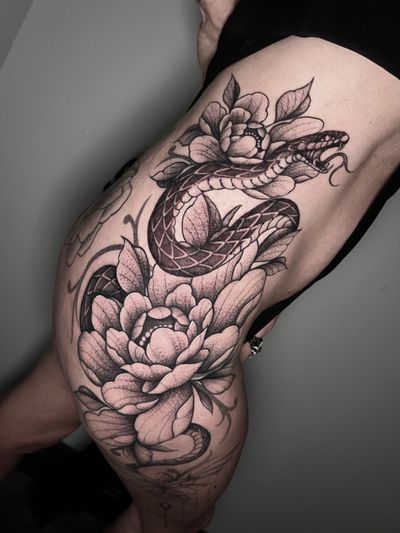 Hamid's stunning illustrative tattoo features a captivating snake surrounded by delicate peony flowers.