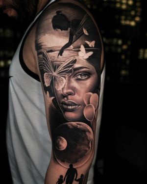 A surreal black and gray tattoo featuring a planet, butterfly, kid, boat, lake, woman, face, balloon, and family elements creatively intertwined. By Ember.